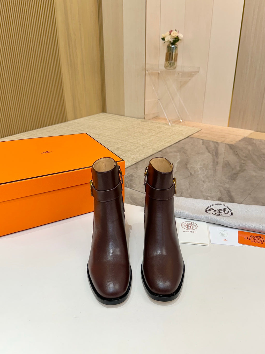 Pair of brown leather heeled ankle boots with gold logo buckle