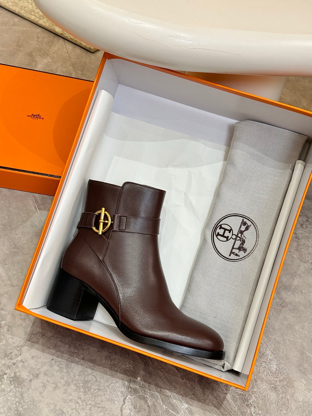 Brown leather heeled ankle boot in orange box with gold logo buckle