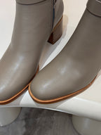 Close-up of light gray ankle boot leather with side zipper and stacked heel