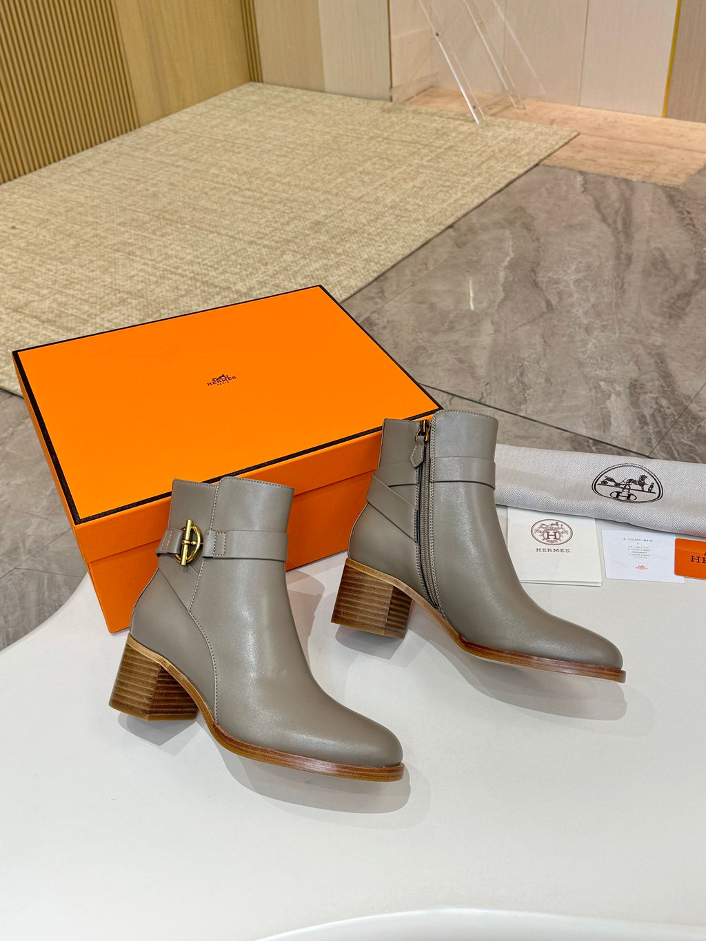 Pair of light gray ankle boots with side gold buckle and stacked heel