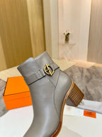 Light gray leather ankle boot with gold buckle strap and wooden heel