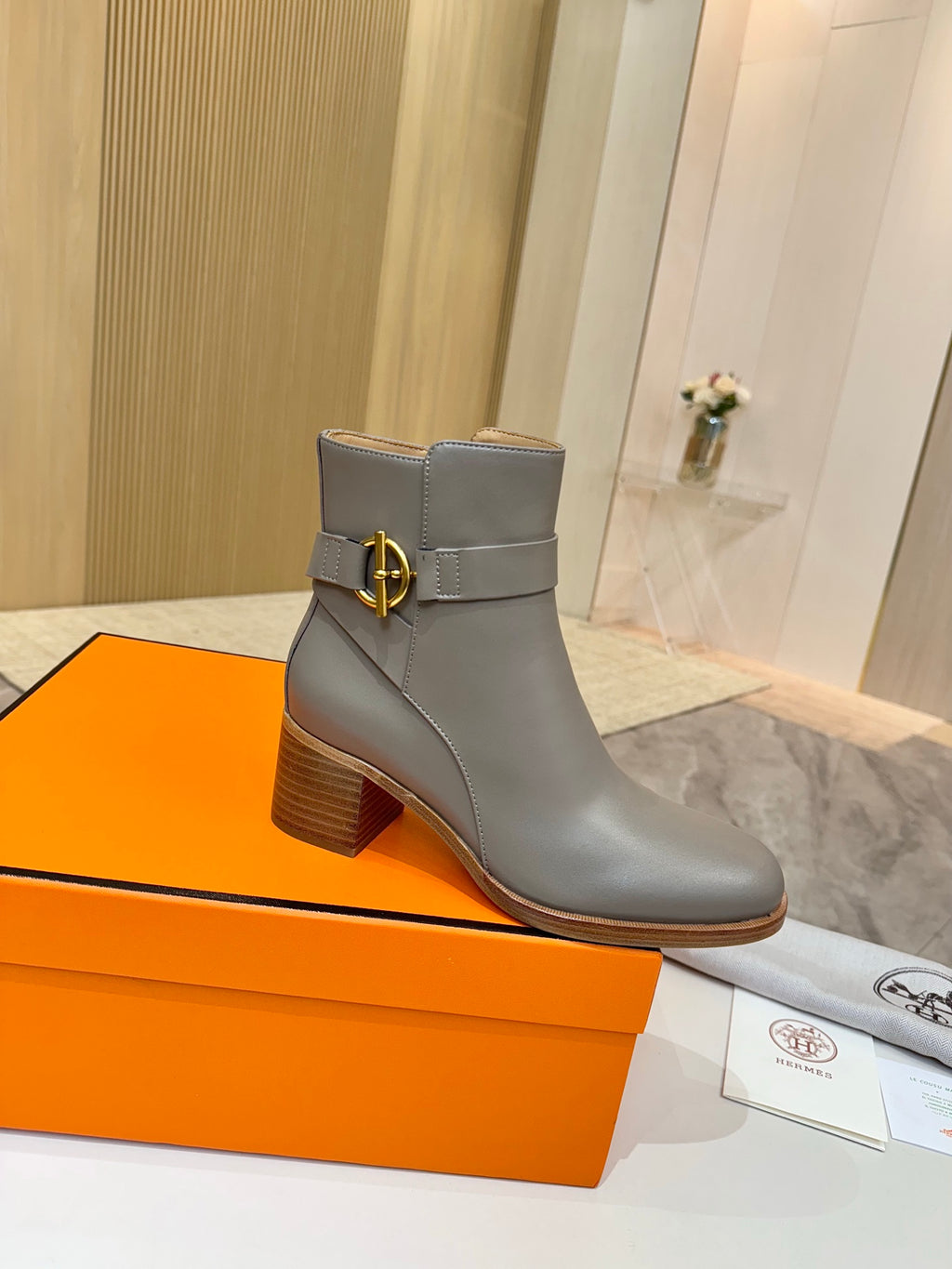 Light gray leather ankle boots with gold buckle at side and stacked wooden heel