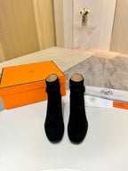 Pair of black suede ankle boots with gold logo accents and block heels