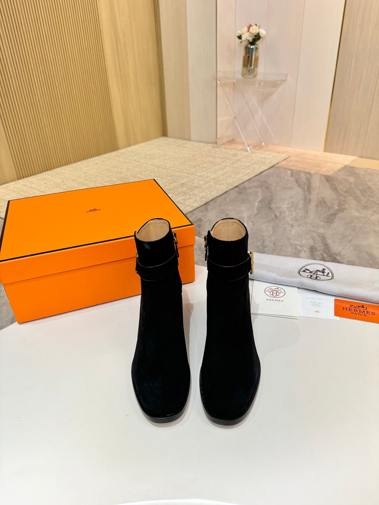 Pair of black suede ankle boots with gold logo accents and block heels