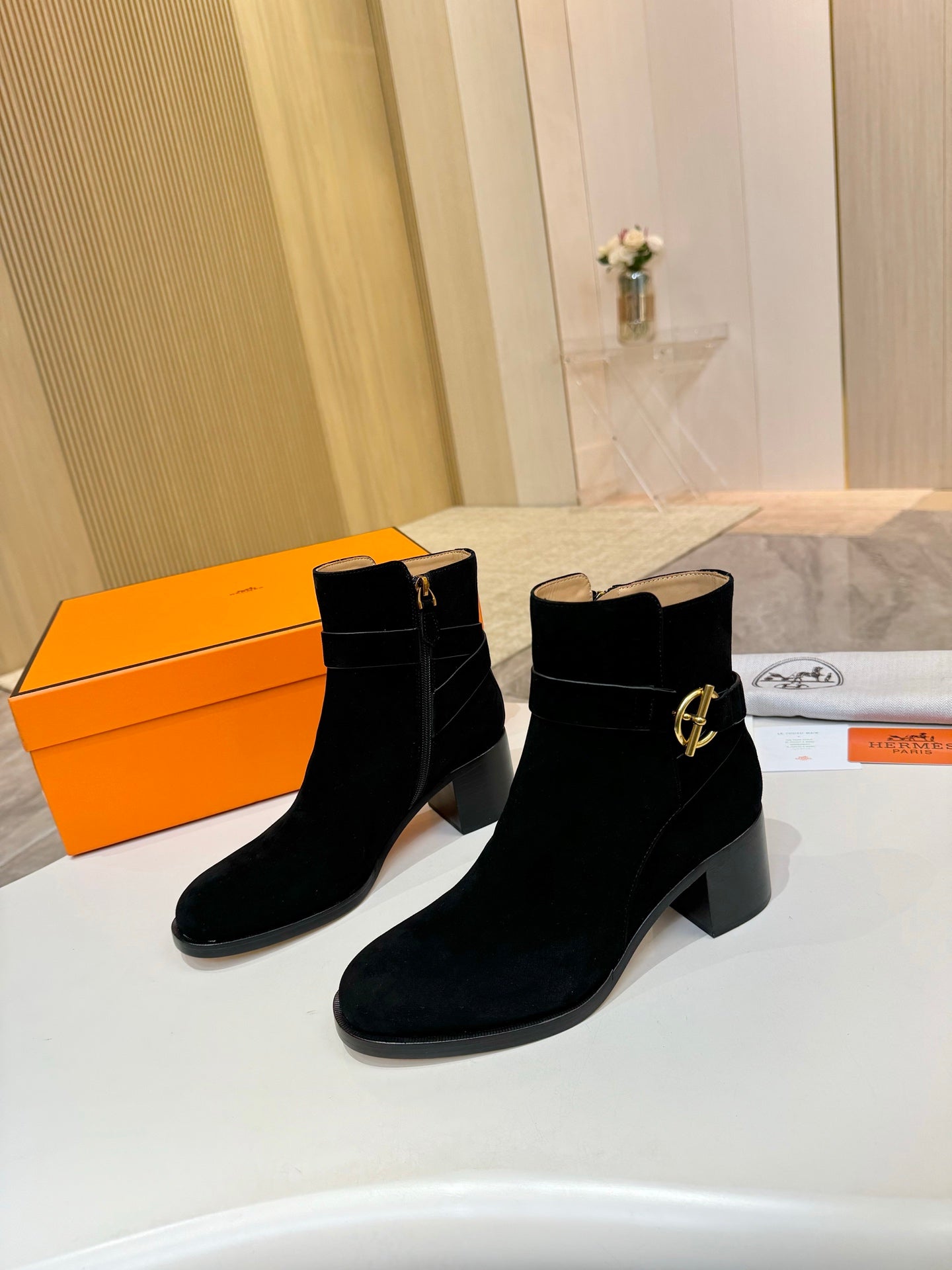 Two black suede ankle boots with gold logo buckle and mid block heel