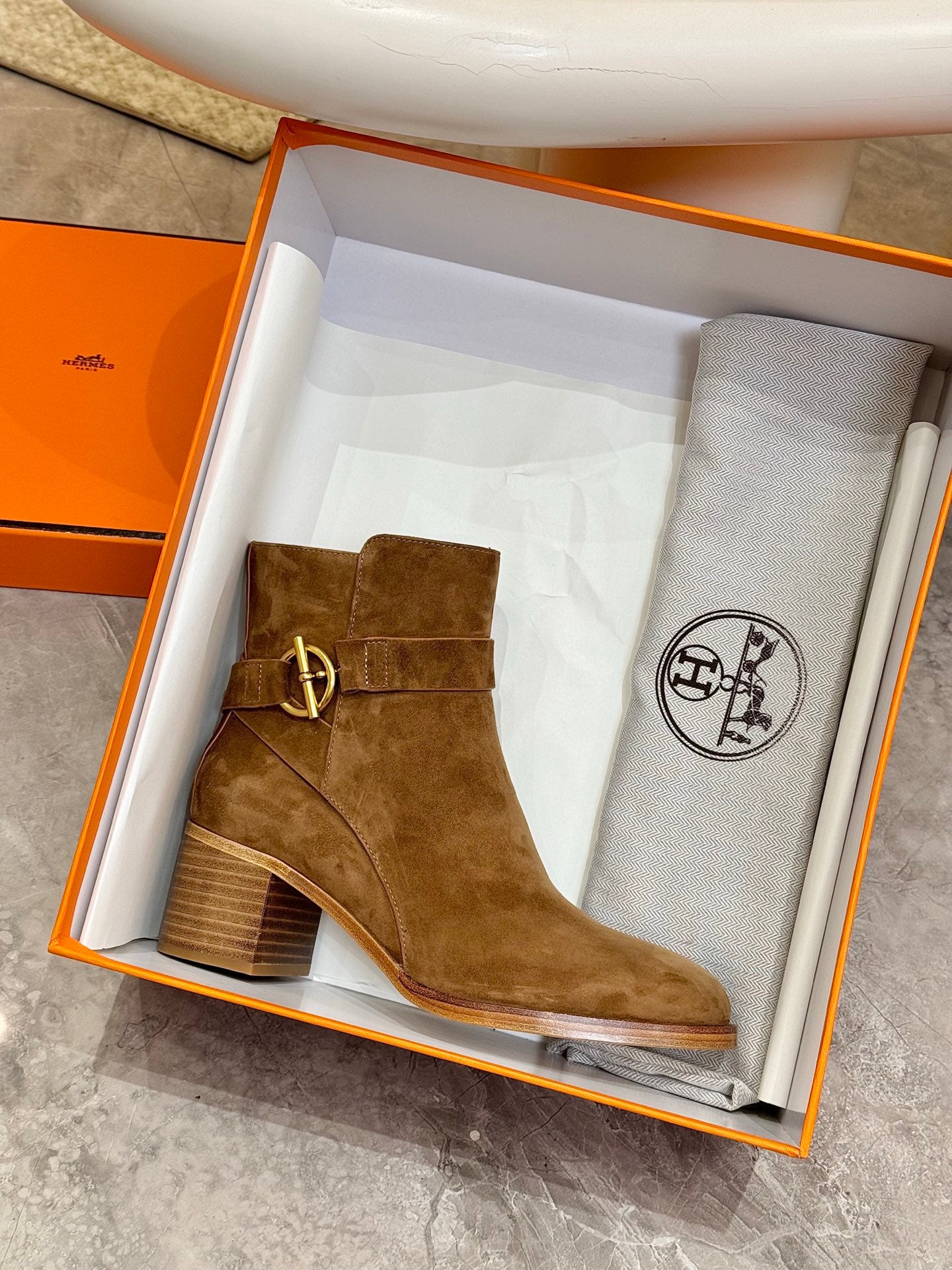 Hermes ladies suede ankle boot in brown, displayed in an orange branded box
