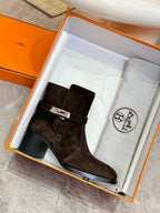 Women’s black suede ankle boots with silver buckle hardware in open box