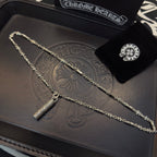 Gold-tone chain necklace with cylindrical pendant on embossed leather-style box