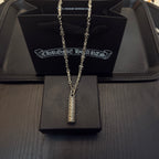Gold-tone chain necklace with cylindrical engraved pendant on gift box