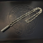 Gold-tone multi-chain necklace with cylindrical pendant on embossed surface