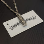 Gold-tone cylindrical pendant necklace with engraved detailing on hanging tag