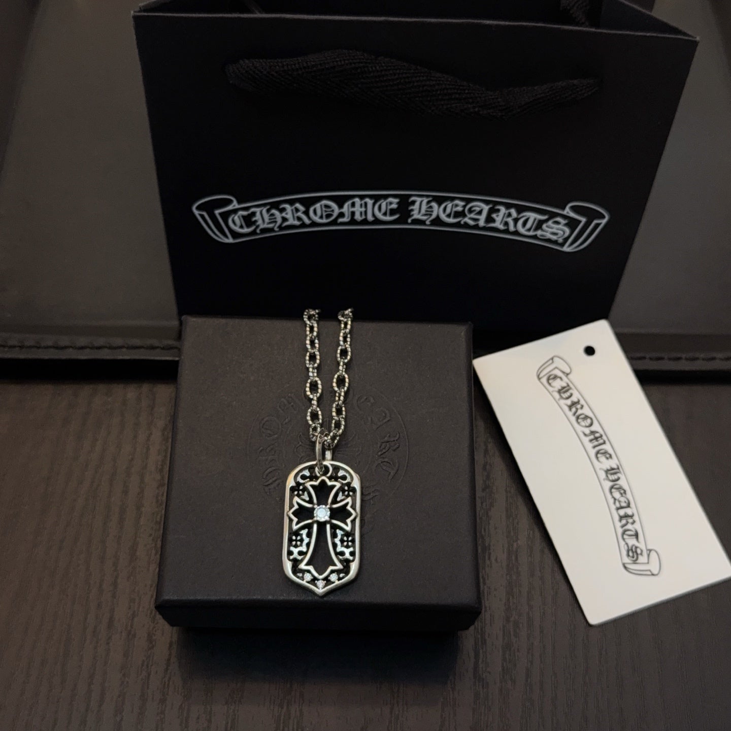 Silver-tone pendant necklace with shield charm on a long chain