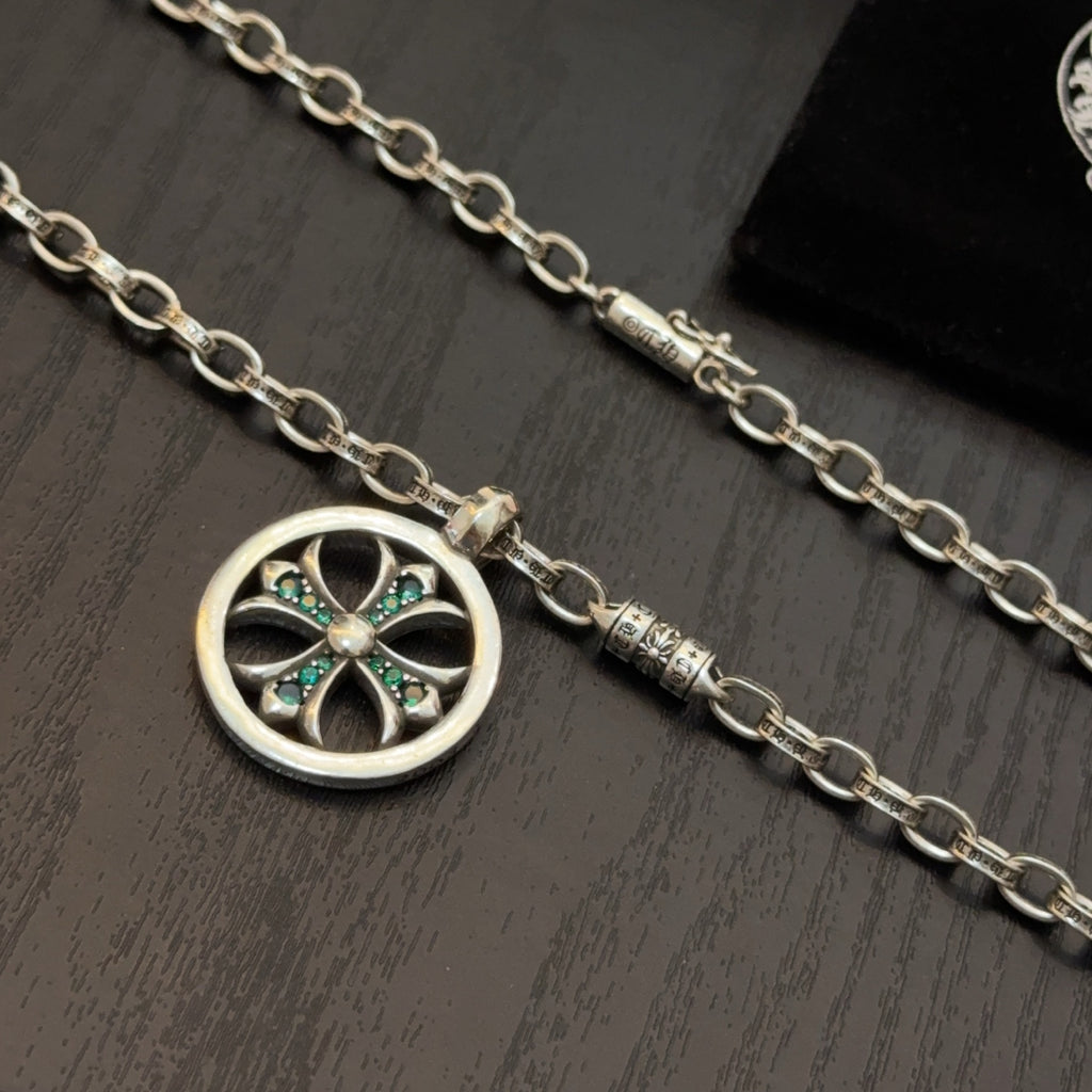 Close-up of silver-tone chain necklace with round pendant and teal stone accents.