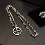 Silver-tone necklace with circular wheel pendant and teal stones, shown on box.