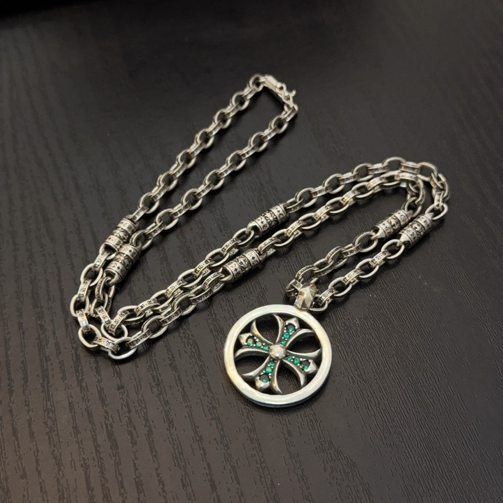 Silver-tone layered chains necklace with circular pendant and teal stone center.