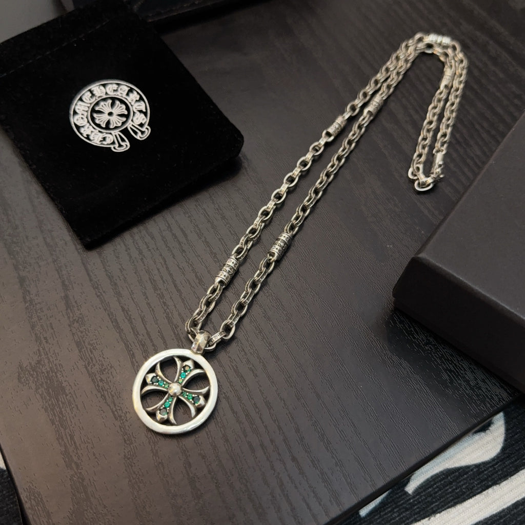 Silver-tone chain necklace with round pendant featuring teal stones, laid on display.