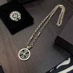 Silver-tone chain necklace with round pendant featuring teal stones, laid on display.