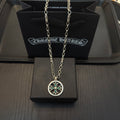 Silver-tone necklace with round pendant and teal insets, shown on gift box.
