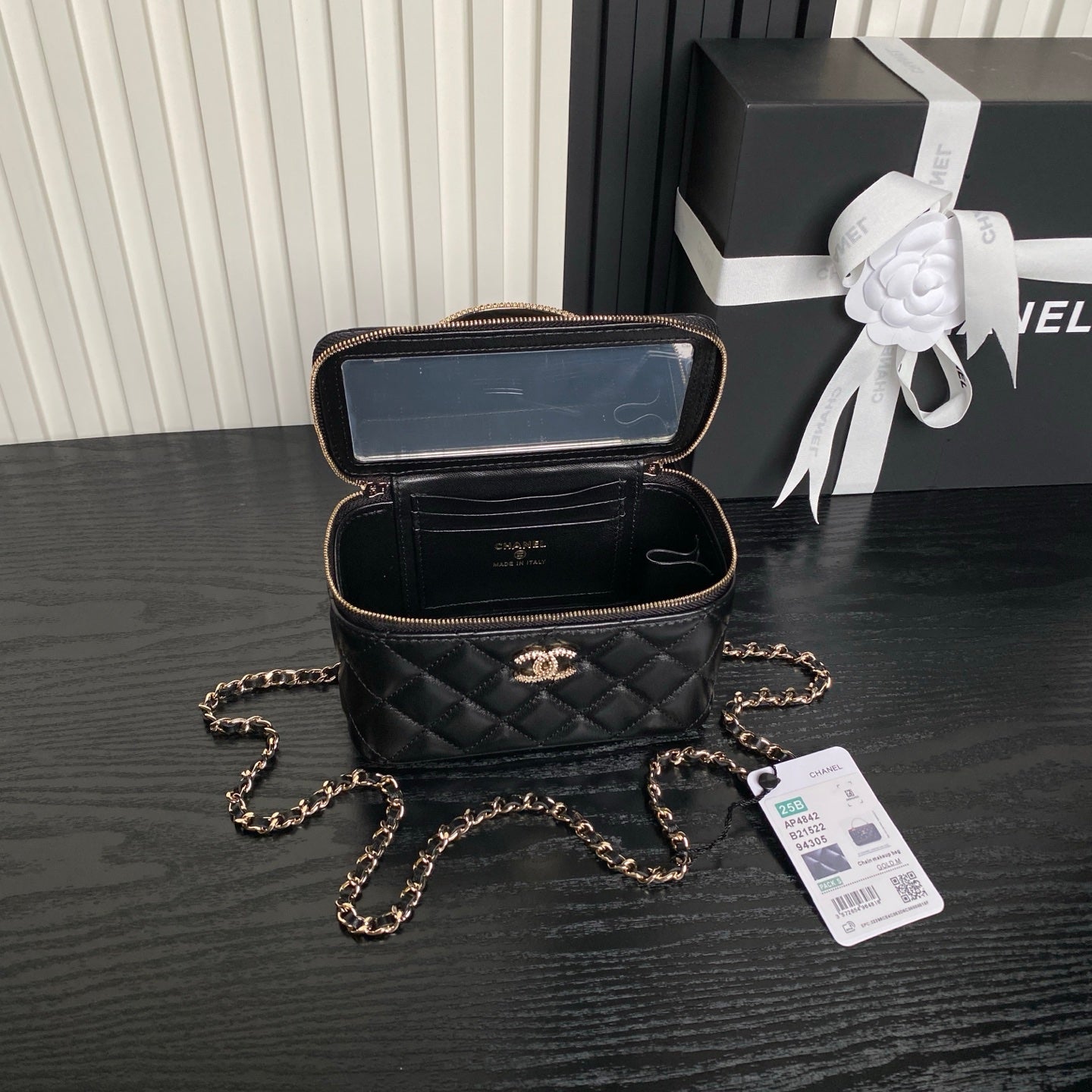 Black quilted mini bag open to show lining and zip pocket, gold chain strap