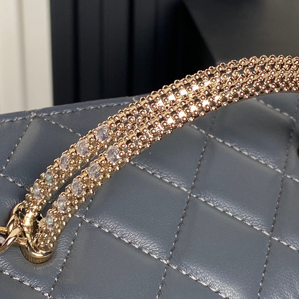 Gold-tone embellished chain strap with rhinestone-like links on blue bag