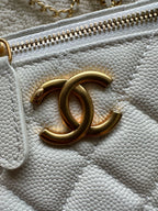 Chanel quilted mini bag close-up of gold zipper and CC logo on white leather