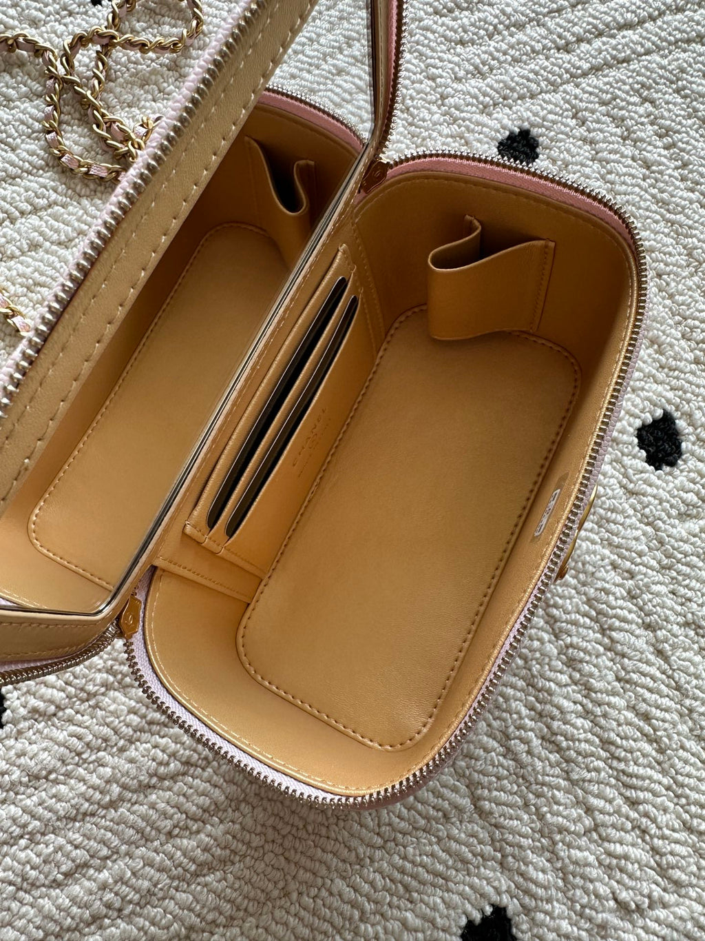 Opened Chanel bag with tan interior slots and zipper pocket lining