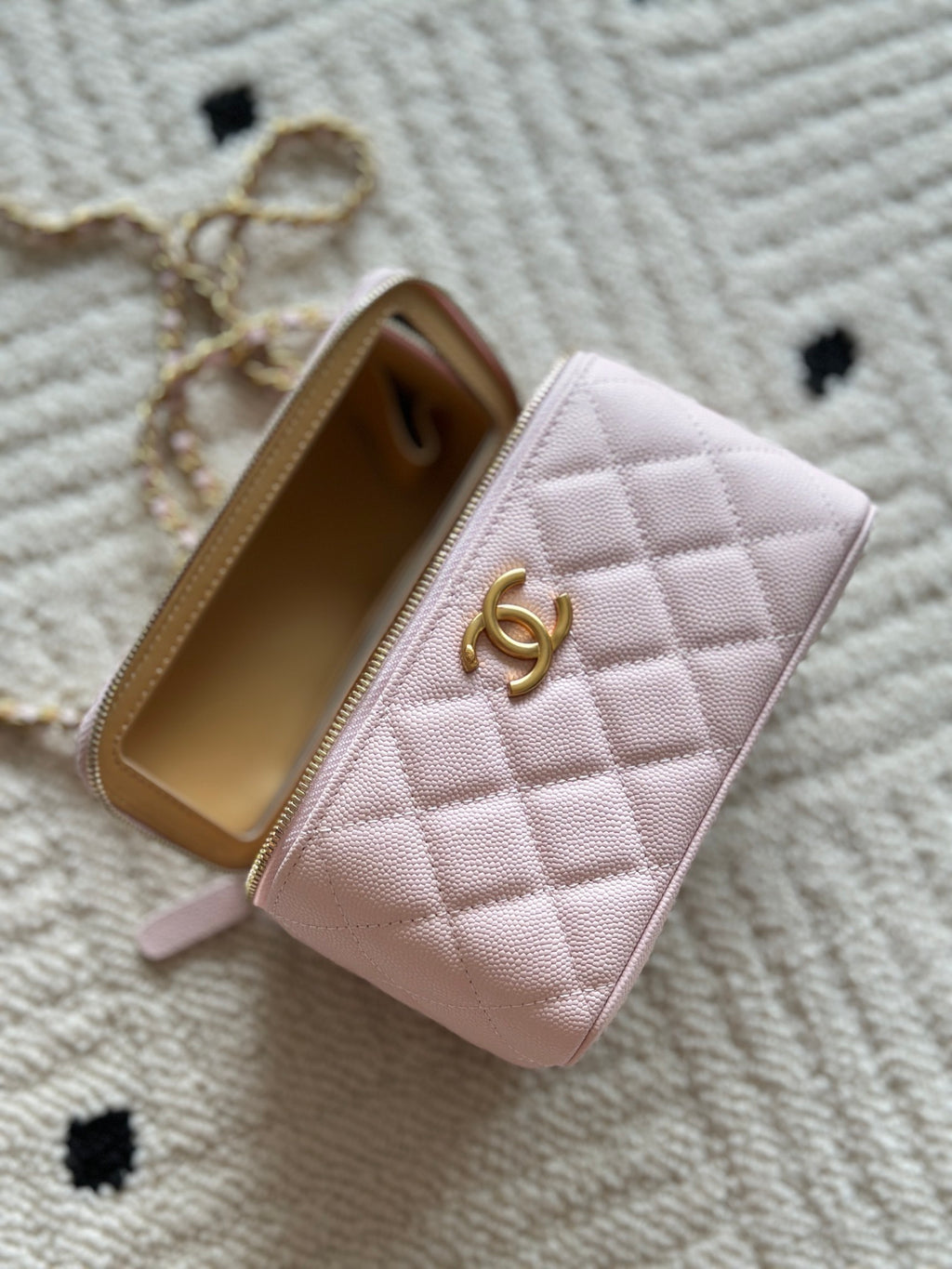 Pink quilted Chanel mini bag open to show beige interior and zipper edge