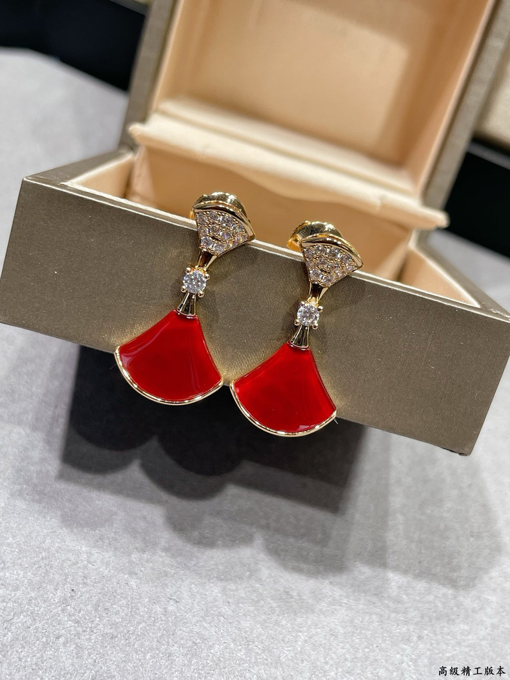 Gold-tone dangling earrings with red teardrop enamel drops and crystal pavé tops