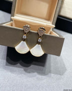Gold-tone dangling earrings with white opal-style drops and crystal pavé tops
