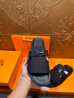 Black slide sandal featuring H buckle on textured upper