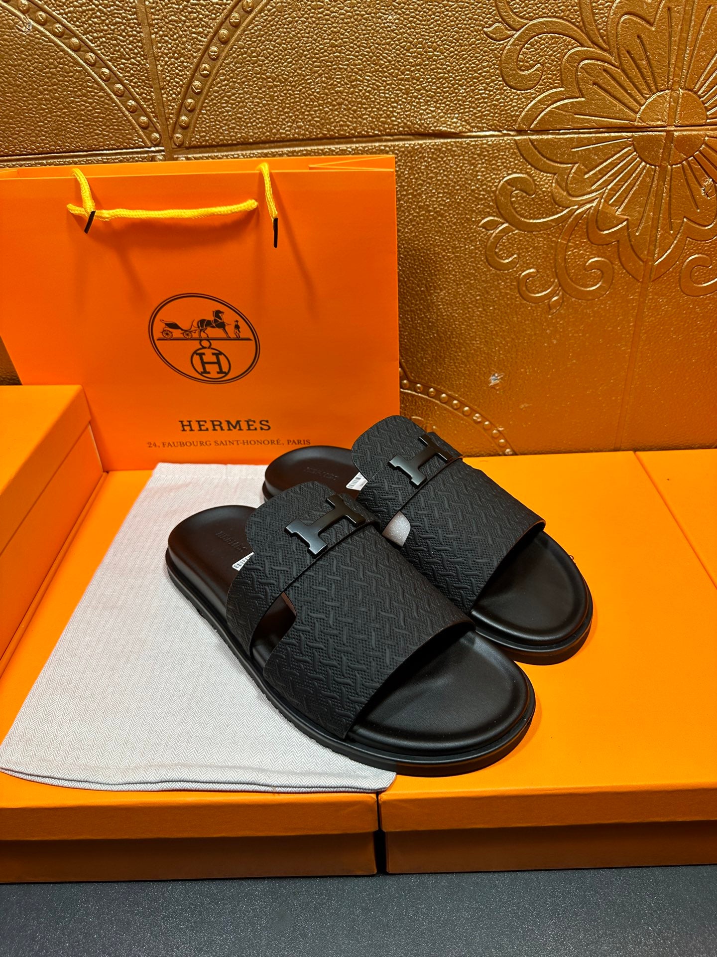Black textured slide sandals with H buckle on strap