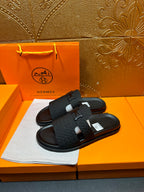 Pair of black slide sandals with H buckle and wide cross strap