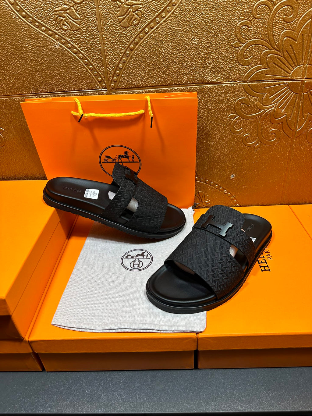 Black textured slide sandals with H buckle on footbed straps