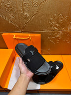 Hermes black slide sandal held in hand, wide H buckle strap