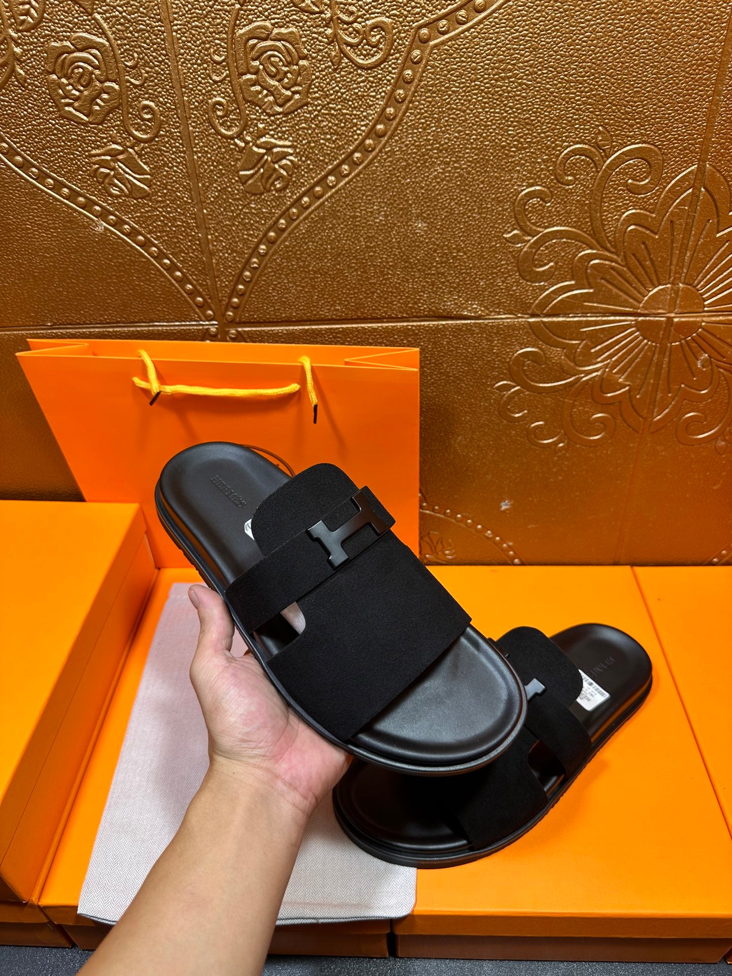 Hermes black slide sandal held in hand, wide H buckle strap