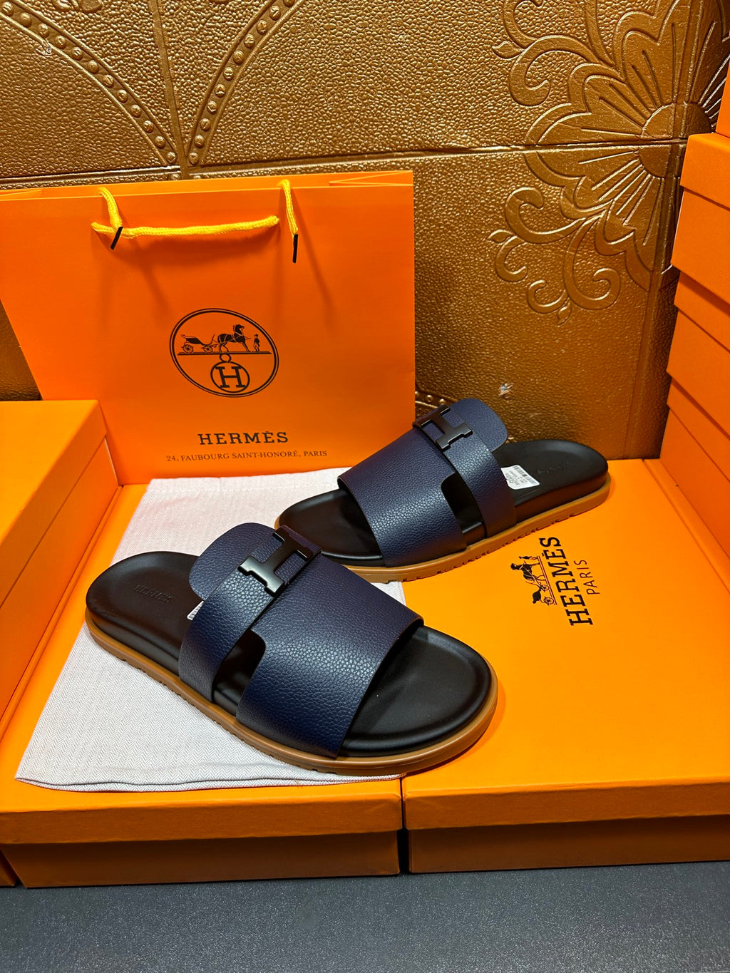 Hermes dark blue slide sandals with wide buckle straps, angled view