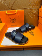 Hermes dark blue slide sandals with wide buckle straps, angled view