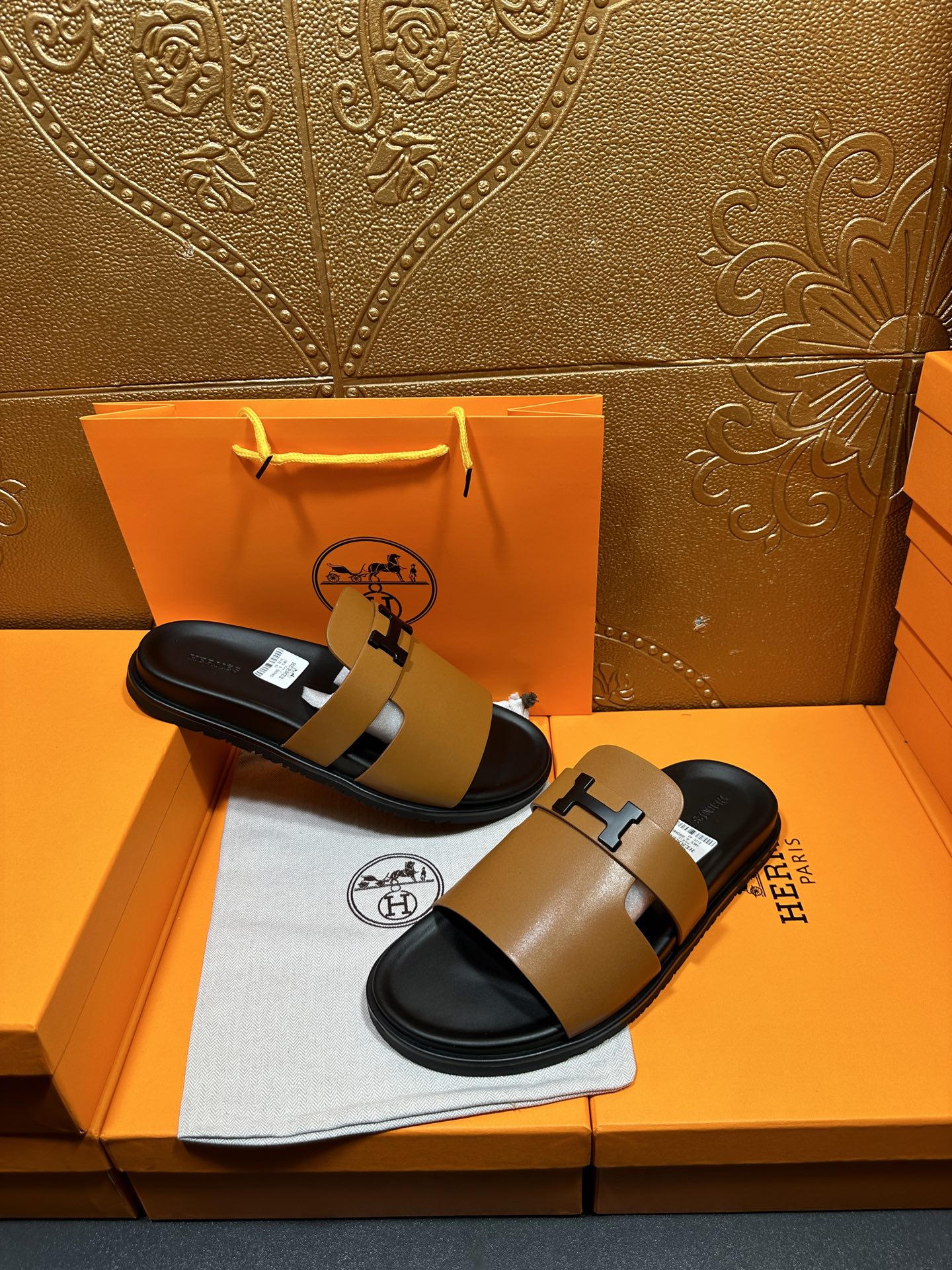Hermes slide sandals with tan leather crossover straps and black H buckle on dark sole