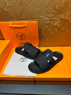 Black textured slide sandals with H buckle on two-strap design