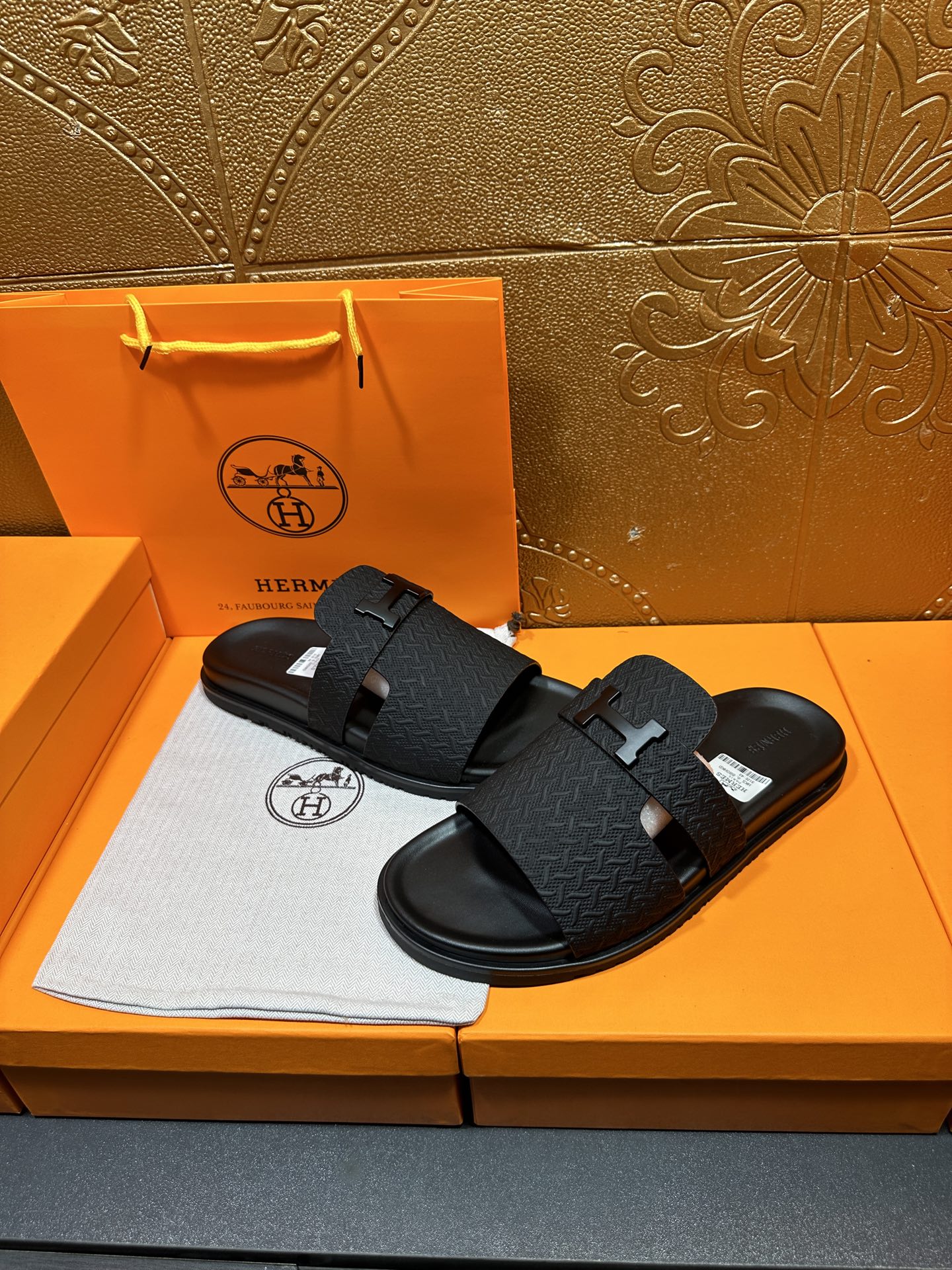 Black textured slide sandals with H buckle on two-strap design