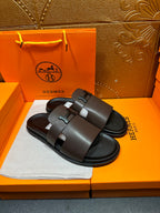 Dark leather slide sandals showing wide front strap and buckle closure.