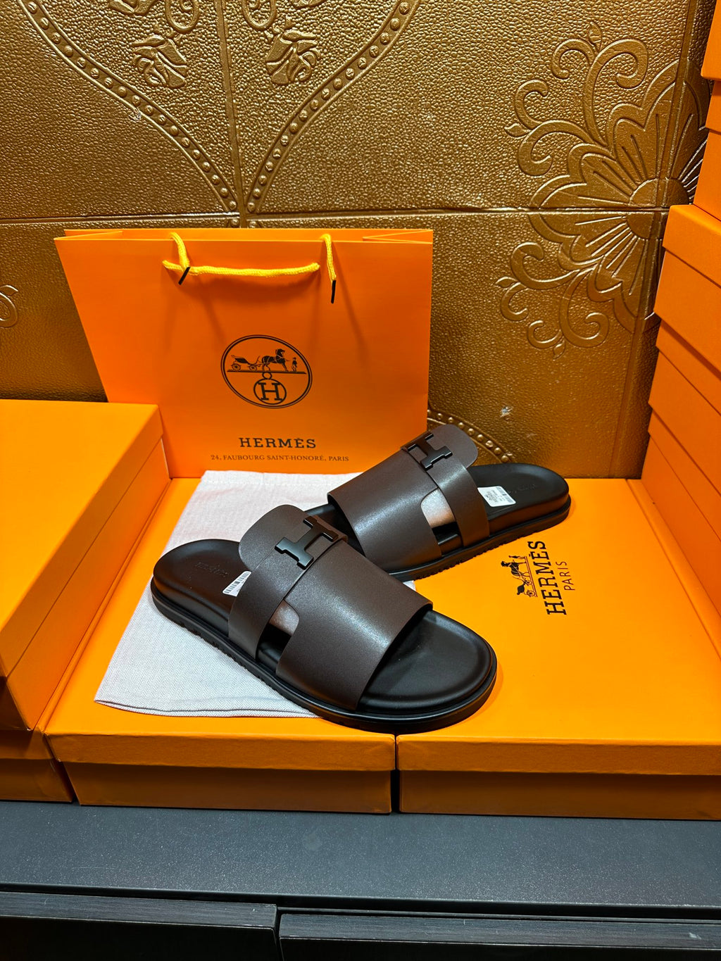 Pair of dark leather slide sandals with wide buckle strap, open toe.
