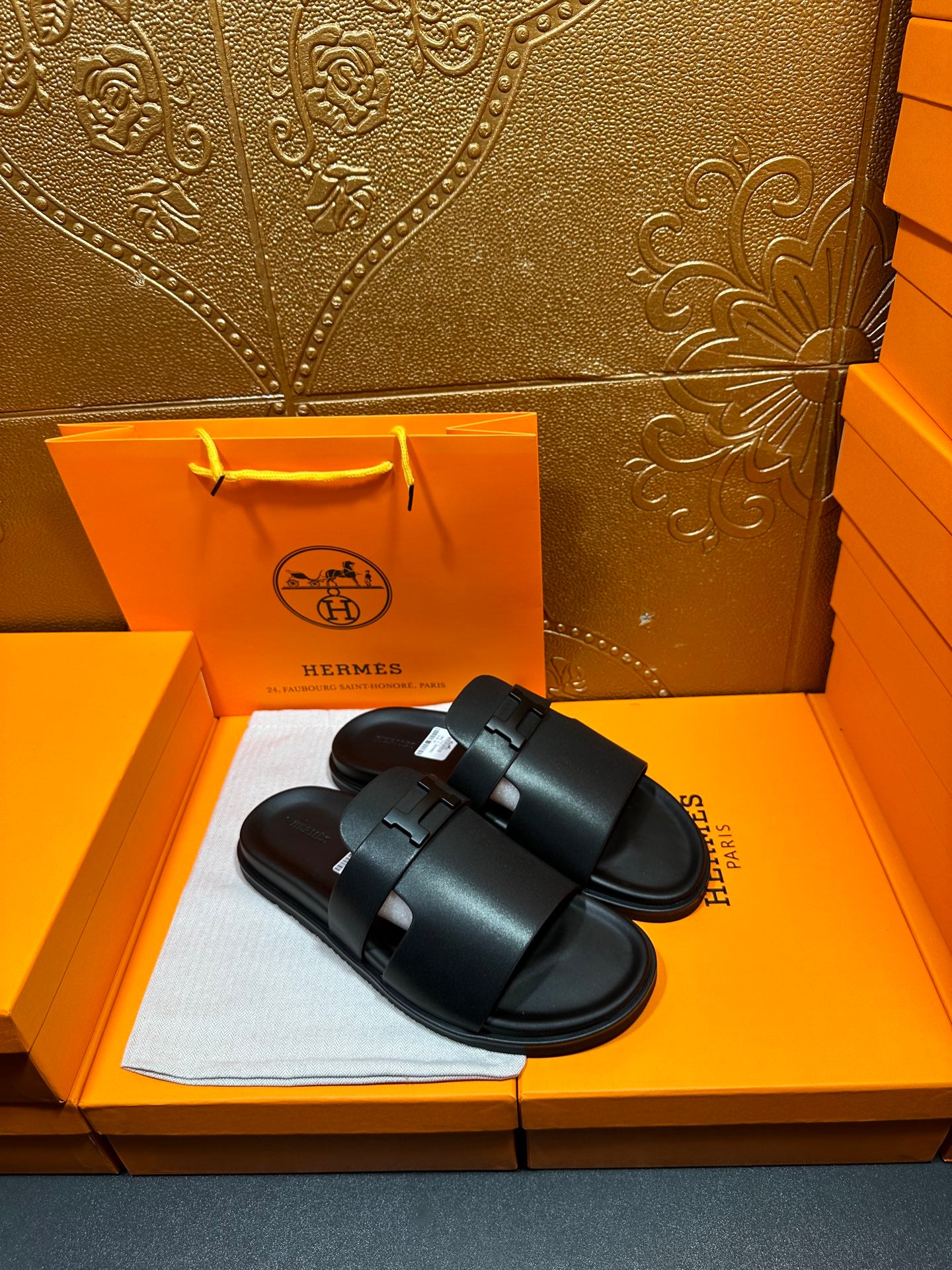 Black leather slide sandals with wide single strap crossing, adjustable buckle detail