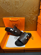 Dark leather slide sandals, wide buckle strap on front, open toe.