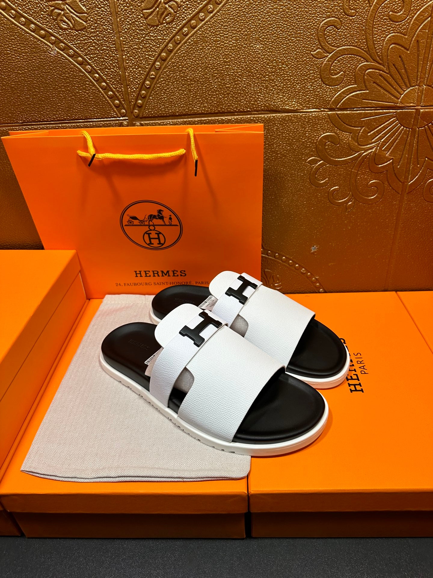 Hermes slide sandals with white straps and black soles, angled top view