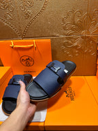 Dark blue leather slide sandals with buckle straps, set on a box