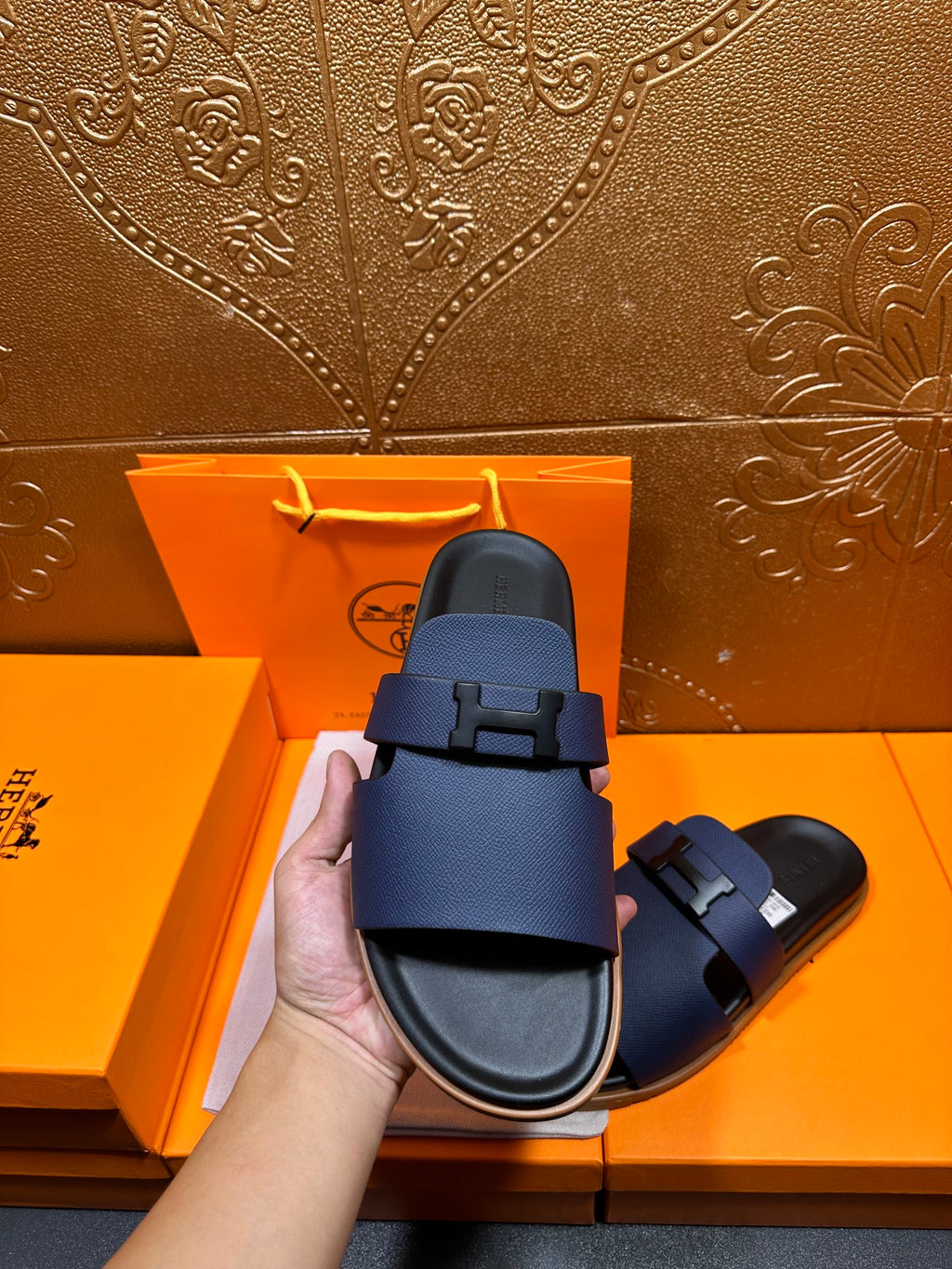 Dark blue leather slide sandal with buckle strap shown on black footbed
