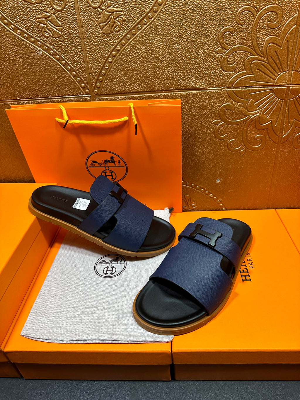 Dark blue leather slide sandals with buckle strap and black sole, shown together