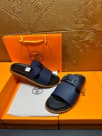 Dark blue leather slide sandals with buckle strap and black sole, shown together