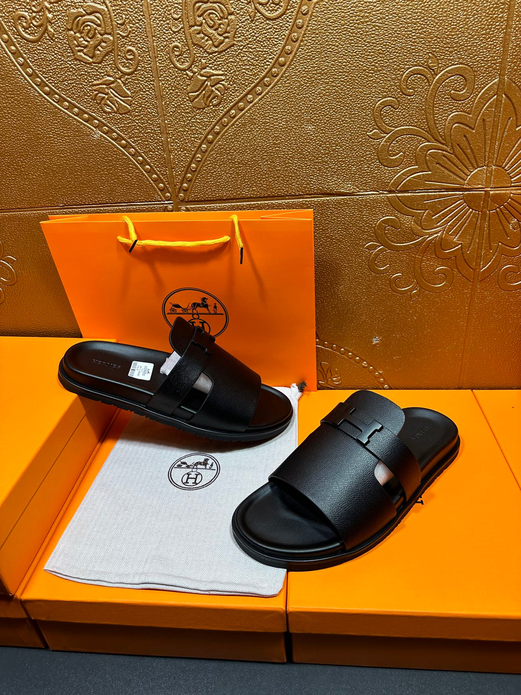 Black leather slide sandals with double strap design and wide buckle closure.